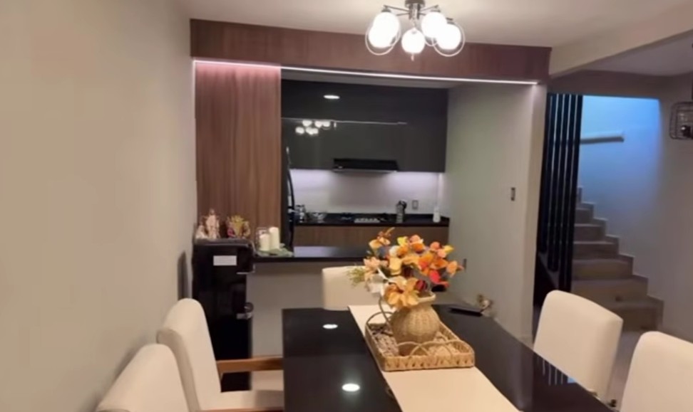 El área del comedor cuenta con una mesa rectangular de cristal oscuro y sillas tapizadas en color beige, perfecto para recibir visitas.
