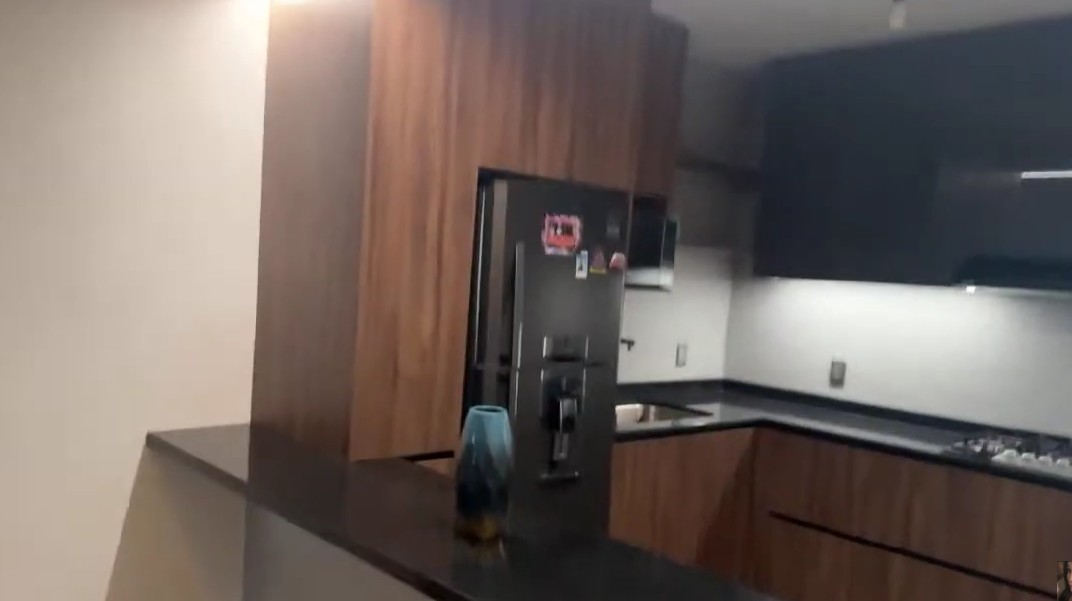 Uno de los espacios más mostrados en sus videos es la cocina, equipada con modernos muebles en tono café y acabados oscuros que contrastan con las paredes blancas.